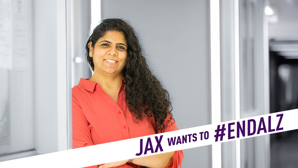 JAX researcher Harpreet Kaur with the banner 'JAX wants to #ENDALZ' across the foreground