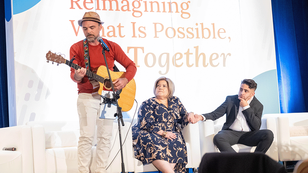 Casey McPherson (left), CEO, To Cure A Rose Foundation, CIO, Everlum Bio, sings song dedicated to his daughter, Rose, titled "Am I Enough?" to kick off Day 1 of NORD Summit. Photo provided by the National Organization for Rare Disorders.